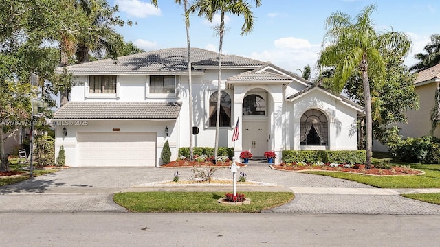 view of front of property featuring a garage, a tiled roof, driveway, and stucco siding