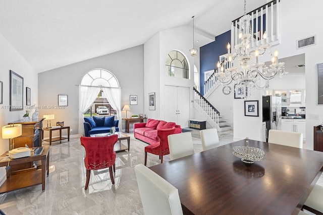 dining space featuring visible vents, marble finish floor, stairs, high vaulted ceiling, and a notable chandelier