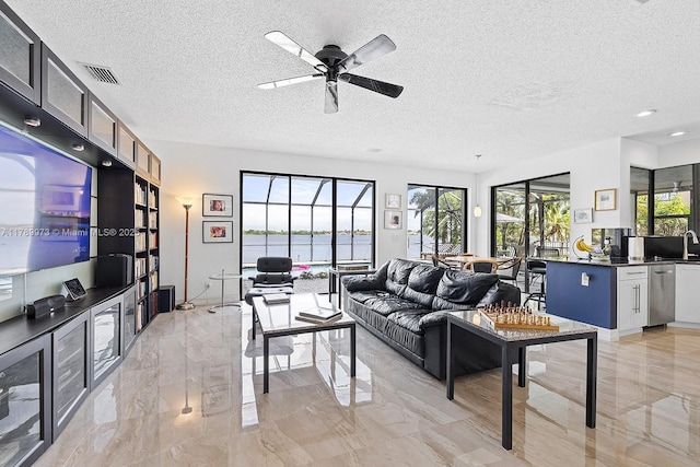 living area with a textured ceiling, visible vents, ceiling fan, and marble finish floor