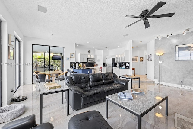 living area with visible vents, ceiling fan, a textured ceiling, and marble finish floor