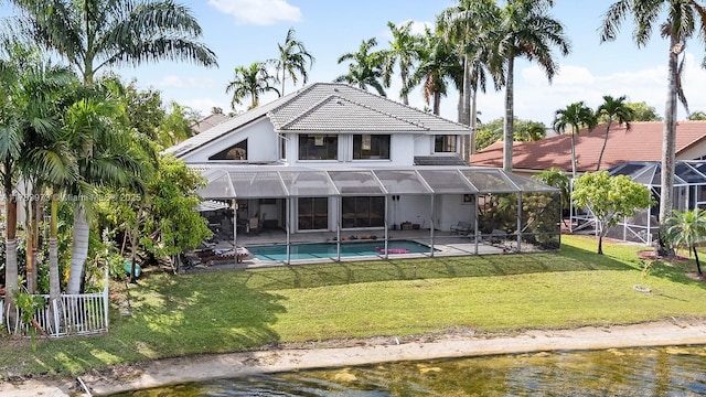rear view of property with a lawn, a tile roof, an outdoor pool, and a patio area