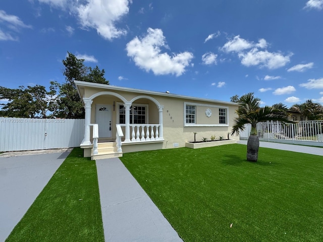 view of front facade with covered porch, fence, a front lawn, and stucco siding