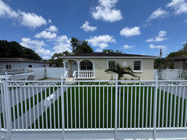 view of front facade featuring a porch, a fenced front yard, a front yard, and stucco siding