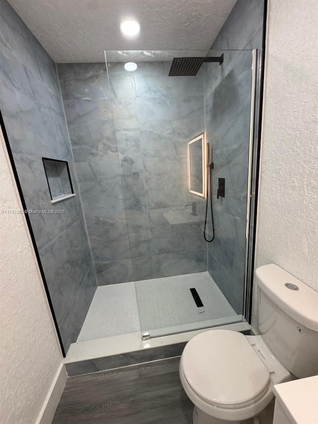 full bathroom with a textured ceiling, a tile shower, and toilet