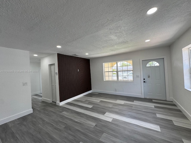 foyer entrance featuring dark wood-type flooring, recessed lighting, a textured ceiling, and baseboards