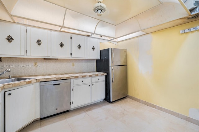 kitchen with light countertops, stainless steel appliances, baseboards, white cabinetry, and backsplash