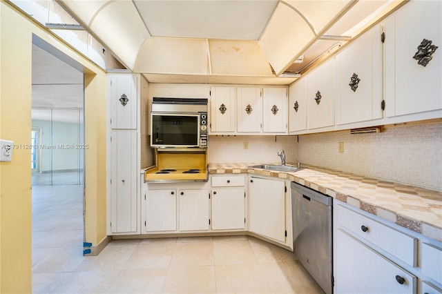 kitchen with a sink, light tile patterned floors, decorative backsplash, and stainless steel dishwasher
