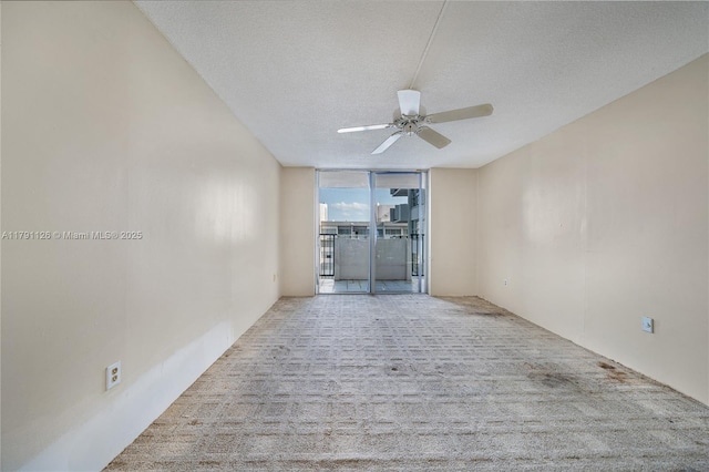 unfurnished room featuring carpet flooring, a ceiling fan, a textured ceiling, and expansive windows