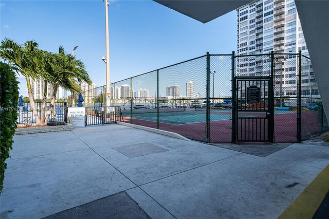 exterior space featuring a tennis court, fence, and a city view