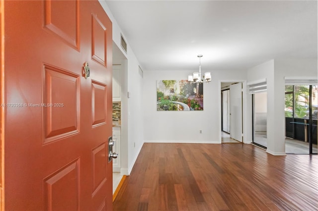 entrance foyer featuring an inviting chandelier, baseboards, wood finished floors, and visible vents