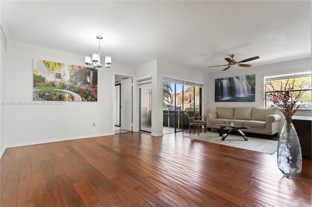 living area with baseboards, ceiling fan with notable chandelier, wood finished floors, and a healthy amount of sunlight