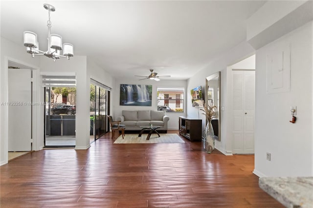 living room featuring baseboards, dark wood-style flooring, and ceiling fan with notable chandelier