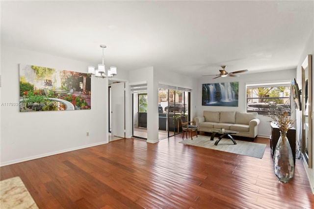 living area with baseboards, ceiling fan with notable chandelier, and wood finished floors