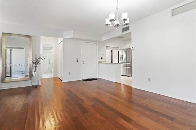 unfurnished living room featuring visible vents, dark wood-style floors, and an inviting chandelier