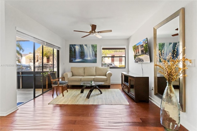 living area featuring baseboards, a ceiling fan, a wealth of natural light, and dark wood-style floors