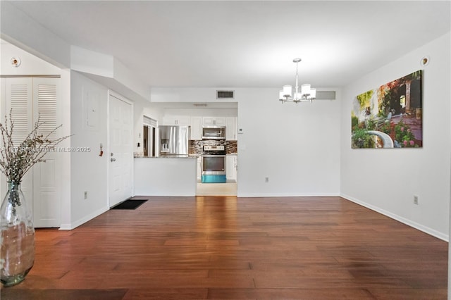 interior space featuring an inviting chandelier, baseboards, wood finished floors, and visible vents