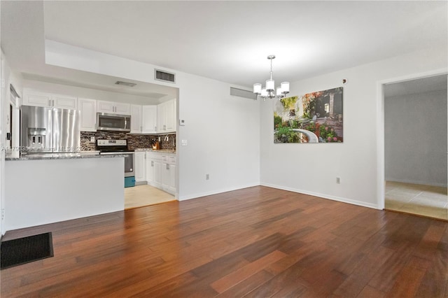 unfurnished living room featuring visible vents, light wood finished floors, and a notable chandelier