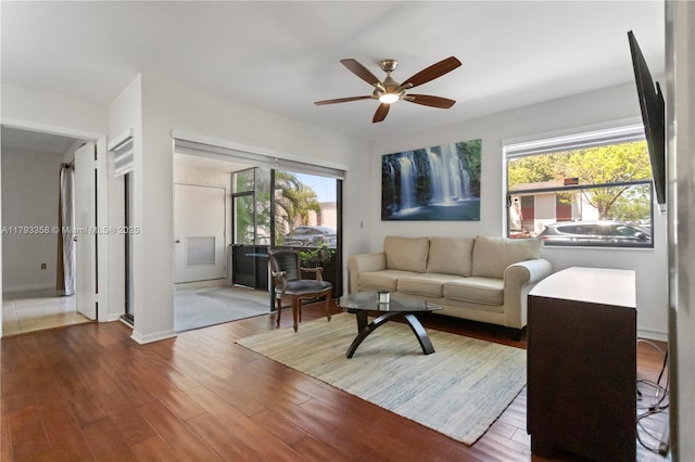 living room featuring baseboards, a ceiling fan, and wood finished floors