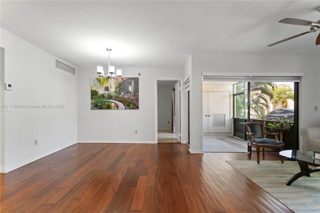 interior space with visible vents, baseboards, ceiling fan with notable chandelier, and wood finished floors