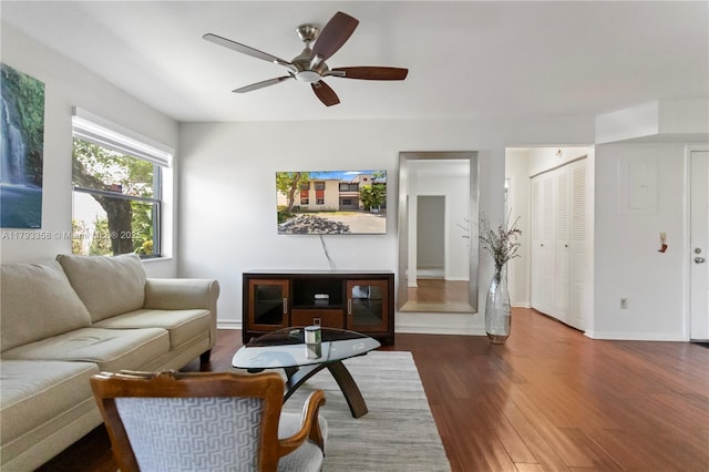 living area featuring baseboards, a ceiling fan, and wood finished floors