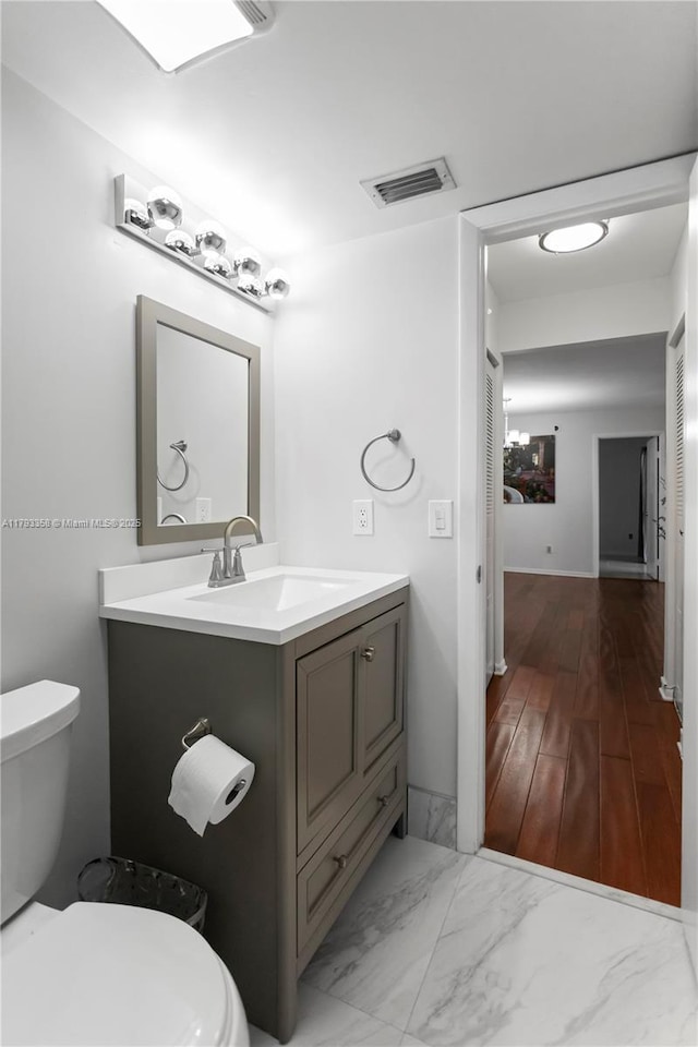 half bathroom featuring visible vents, marble finish floor, toilet, and vanity
