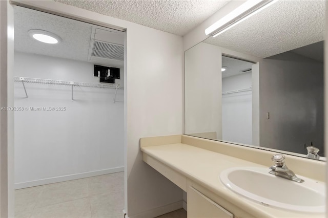 bathroom with a walk in closet, tile patterned flooring, vanity, and a textured ceiling