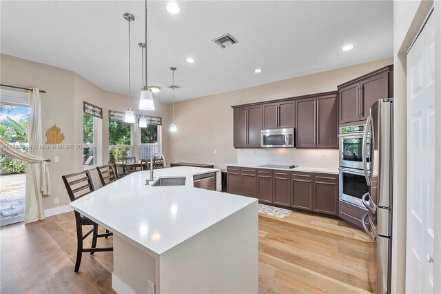 6017 NW 56th Cir, Coral Springs, FL 33067 - kitchen featuring appliances with stainless steel finishes, light wood-type flooring, a sink, a kitchen island with sink, and healthy amount of natural light