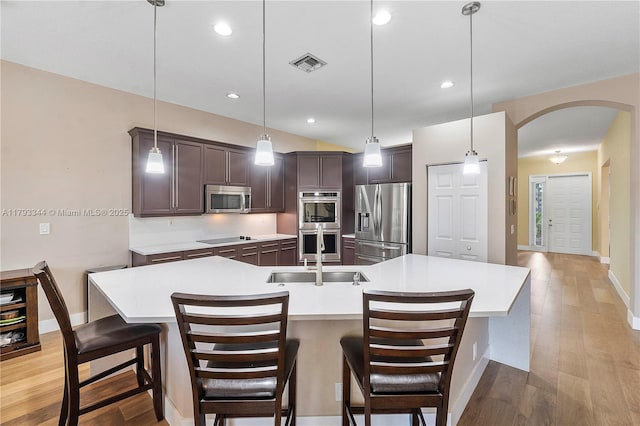 6017 NW 56th Cir, Coral Springs, FL 33067 - kitchen featuring appliances with stainless steel finishes, arched walkways, dark brown cabinetry, light countertops, and light wood-type flooring