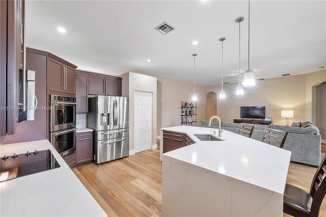6017 NW 56th Cir, Coral Springs, FL 33067 - kitchen with appliances with stainless steel finishes, a sink, arched walkways, light wood-style floors, and recessed lighting