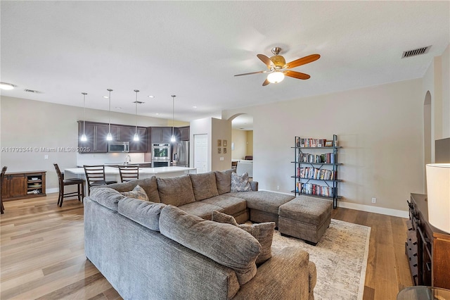 6017 NW 56th Cir, Coral Springs, FL 33067 - living room with arched walkways, ceiling fan, light wood-style floors, and beverage cooler