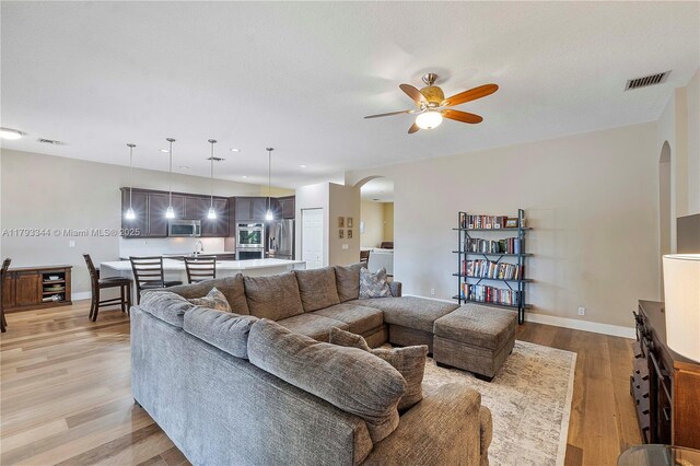 6017 NW 56th Cir, Coral Springs, FL 33067 - living room with arched walkways, ceiling fan, light wood-style floors, and beverage cooler