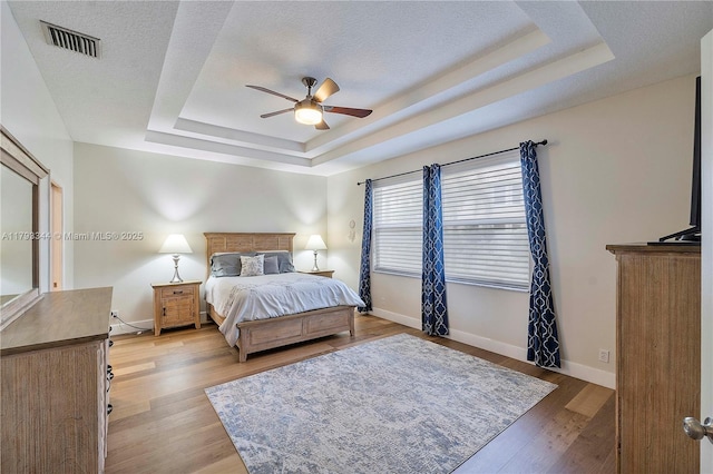 6017 NW 56th Cir, Coral Springs, FL 33067 - bedroom with a tray ceiling, baseboards, light wood finished floors, a textured ceiling, and ceiling fan