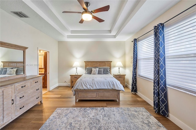 6017 NW 56th Cir, Coral Springs, FL 33067 - bedroom featuring a raised ceiling, baseboards, wood finished floors, a ceiling fan, and connected bathroom