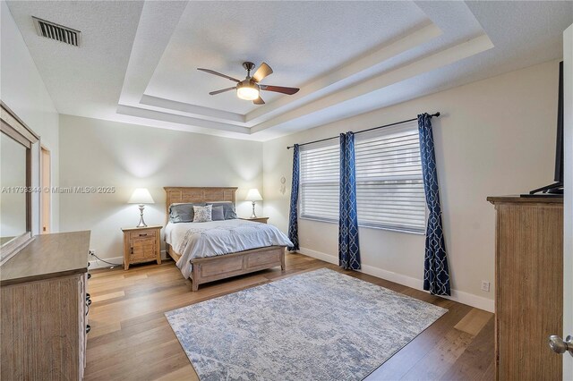 6017 NW 56th Cir, Coral Springs, FL 33067 - bedroom with a tray ceiling, light wood-style flooring, a ceiling fan, and a textured ceiling