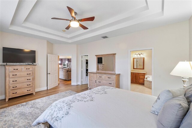 6017 NW 56th Cir, Coral Springs, FL 33067 - bedroom featuring a tray ceiling, light wood-style floors, ensuite bathroom, baseboards, and ceiling fan