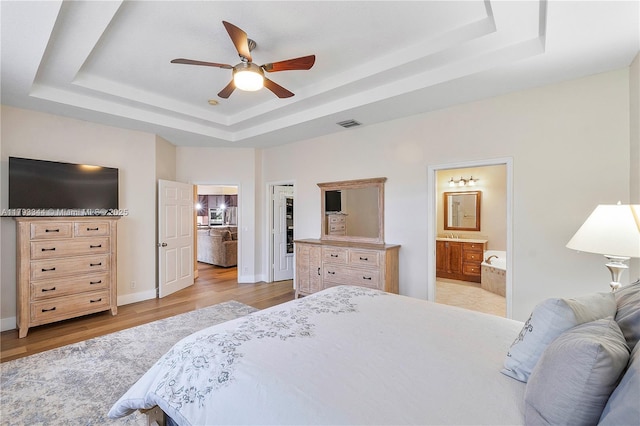 6017 NW 56th Cir, Coral Springs, FL 33067 - bedroom featuring a raised ceiling, light wood-style flooring, ensuite bathroom, and ceiling fan