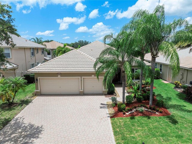 6017 NW 56th Cir, Coral Springs, FL 33067 - view of front of property with a front yard, an attached garage, decorative driveway, stucco siding, and a tiled roof