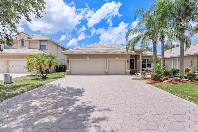 6017 NW 56th Cir, Coral Springs, FL 33067 - mediterranean / spanish-style home with stucco siding, decorative driveway, a tiled roof, and an attached garage