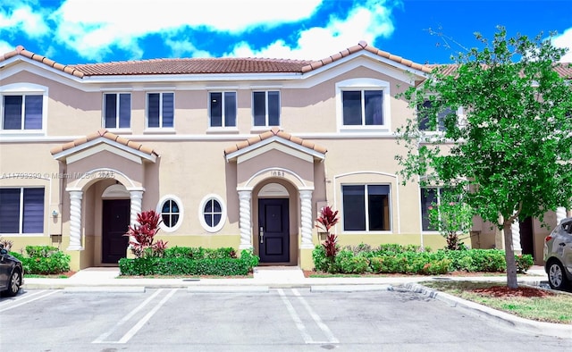 mediterranean / spanish house with a tiled roof, uncovered parking, and stucco siding
