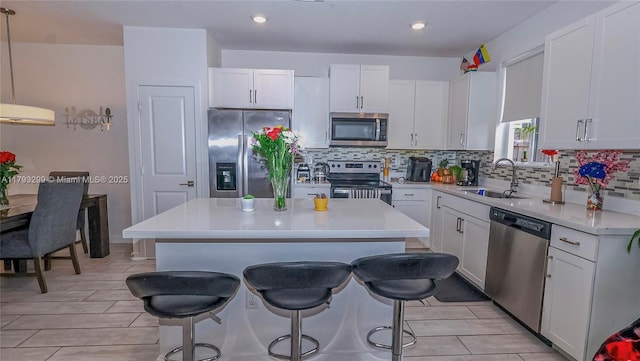 kitchen with light countertops, a sink, a kitchen breakfast bar, and stainless steel appliances