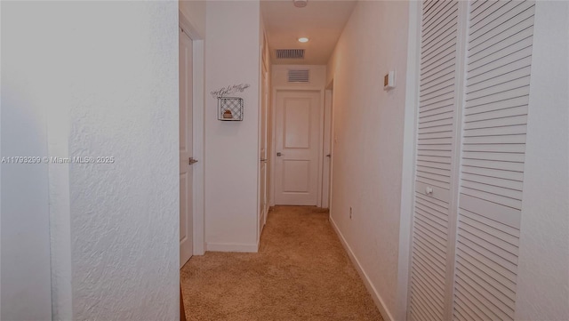 hallway featuring visible vents, carpet flooring, and baseboards