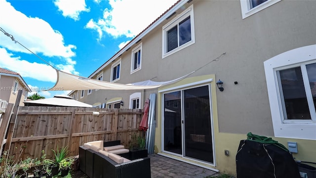 rear view of house featuring fence, stucco siding, and a patio area