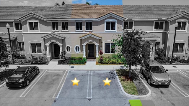 view of front of home featuring uncovered parking, stucco siding, and a tile roof