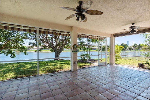 unfurnished sunroom featuring a ceiling fan and a water view