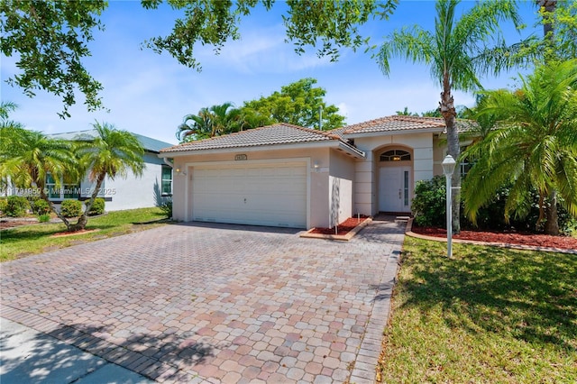 mediterranean / spanish house featuring a garage, stucco siding, decorative driveway, and a tile roof