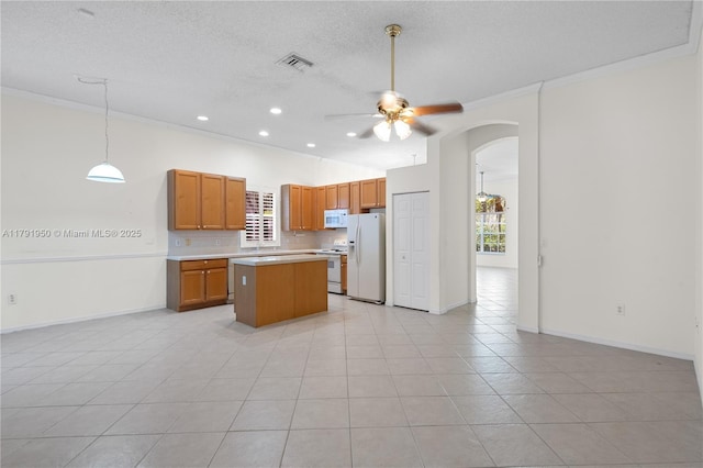 kitchen featuring crown molding, ceiling fan, white appliances, arched walkways, and light countertops