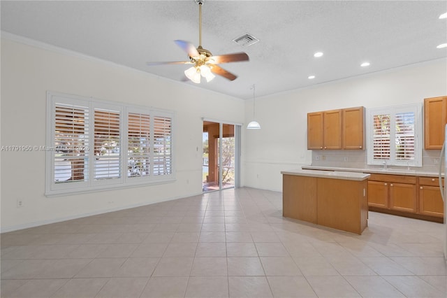 kitchen with a center island, light countertops, ceiling fan, and a wealth of natural light