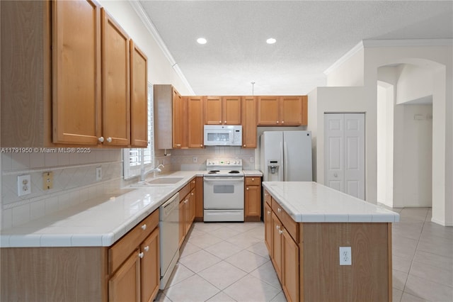 kitchen with white appliances, light tile patterned flooring, ornamental molding, and tasteful backsplash