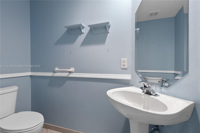bathroom with toilet, visible vents, and a sink