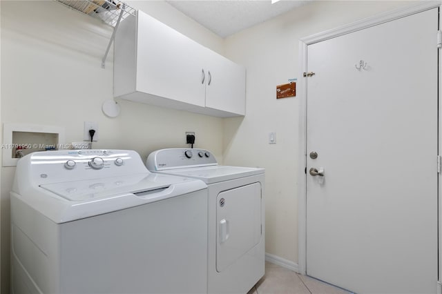 clothes washing area featuring light tile patterned floors, cabinet space, and washer and clothes dryer
